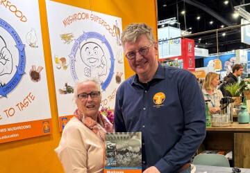 Mark den Ouden van Mushroom Office met een vertegenwoordiger van AgroLingua op de Champignondagen 2026, met het boek Champignonsignalen in beeld.